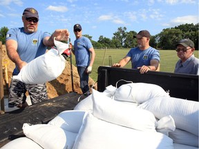 OPP Aux. officer Shawn Brazil, left, and other OPP auxiliary officers help homeowner Larry Foster, right, of Silver Avenue in Cotterie Park with dozens of sandbags Wednesday.  The Essex County OPP Auxiliary Unit filled hundreds of sandbags for residents living in areas vulnerable to flooding.