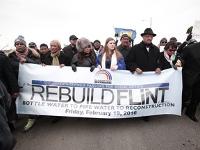 Death in the taps. Rev. Jesse Jackson (right, in hat) walks in a national march on Feb. 19, 2016, to highlight the push for clean water in Flint, Mich.