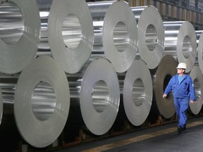 FILE - A worker walks among rolls of semi-finished aluminum at the Alcoa aluminum factory October 24, 2006 in Szekesefehervar, Hungary.