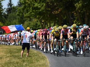 A man holding the French national flag watches the pack riding during the fourth stage of the 106th edition of the Tour de France cycling race between Reims and Nancy, eastern France, on July 9, 2019.