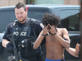 One of three people arrested at the Travelodge in South Windsor on July 9, 2019, hides his face while being led away by Windsor police officers.