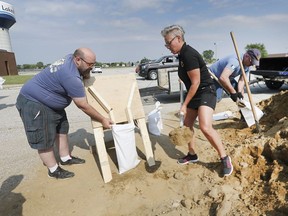 Helping hands. Lakeshore resident Roderick White, left, gets a hand filling sandbags from Jennifer Poisson, a member of the Lakeshore Police Committee, and OPP Auxiliary Const. Shawn Brazil on July 10, 2019 at the former Belle River Arena on Rourke Line Road. Members of the Essex county O.P.P. auxiliary unit and Lakeshore Police committee were at various locations throughout the municipality helping with the flood prevention effort.