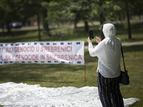 A woman takes a photo of the display as the local Bosnian community pay their respects during a ceremony marking the Srebrenica Genocide at the Srebrenica monument at Jackson Park on July 13,  2019.
