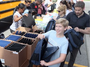 Riley Huffman, front, and his dad Jeff Huffman of National Bank, participate with dozens of other volunteers during the annual Fill the Bus Day, part of the Back to School Back Pack and Supplies Drive held at Staples on Walker Road Saturday morning.