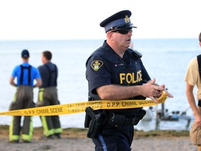 OPP Const. Christian Cortese places tape around a section of Lakewood Park in Tecumseh during the search for a missing boater on Lake St. Clair on Aug. 18.