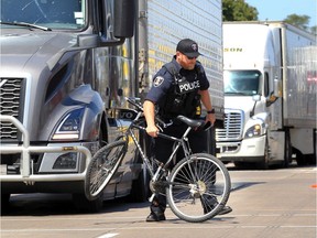 A Windsor Police officer removes a bicycle from in front of a Volvo tractor-trailer on southbound Huron Church Road at Tecumseh Road West Thursday afternoon. Windsor firefighters assisted Essex-Windsor EMS paramedics who transported the cyclist to hospital.