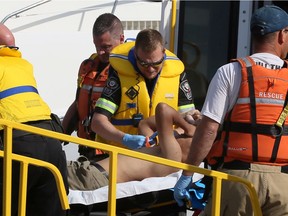 Lakeshore, Ontario. August 24, 2019 -- Essex-Windsor EMS paramedics, Lakeshore firefighters and OPP assist an injured boater at Belle River Marina.  Two men were taken to hospital with serious leg injuries.