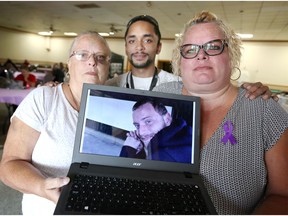 Debora McLean, left, Wesley Sinclair and Candice McCowin, hold a laptop showing McLean's son Graeme McLean, who died of a drug overdose last year at the age of 27. McCowin is Graeme's sister and Wesley is Graeme's nephew. The family was attending the International Overdose Awareness Day Memorial Dinner at Average Joe's Friday.