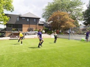 Glen Martins watches daughters Bella, 10, Tienna, 12 and Sofia, 8, practise their ball-handling skills in the sideyard of their Byron home which boasts an artificial turf soccer pitch.  (Mike Hensen/The London Free Press)