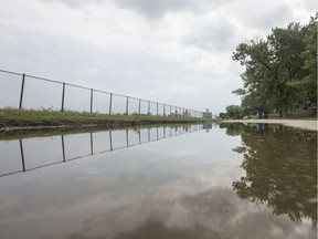 Water from the Detroit River forms a large puddle next to a fenced off area at Ambassador Park in West Windsor, Tuesday, August 6, 2019.