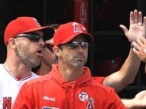 Manager Brad Ausmus #12 of the Los Angeles Angels congratulates Michael Hermosillo #21 of the Los Angeles Angels after he scored on a double hit by Jared Walsh #25 in the second inning at Angel Stadium of Anaheim on September 15, 2019 in Anaheim, California.