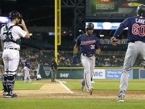 Jake Cave #60 of the Minnesota Twins and LaMonte Wade Jr. #30 score past catcher Jake Rogers #34 of the Detroit Tigers on a single by Willians Astudillo during the seventh inning at Comerica Park on September 24, 2019 in Detroit, Michigan.