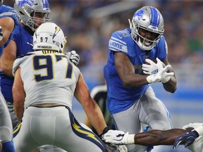 Kerryon Johnson of the Detroit Lions looks for yards during a second quarter run behind Joey Bosa of the Los Angeles Chargers at Ford Field on September 15, 2019 in Detroit, Michigan.