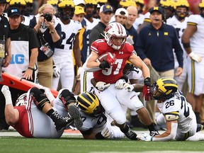 Garrett Groshek of the Wisconsin Badgers is brought down by J'Marick Woods of the Michigan Wolverines during the first half at Camp Randall Stadium on September 21, 2019 in Madison, Wisconsin.