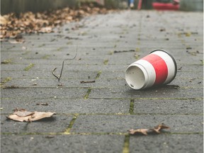 A used coffee cup on a sidewalk illustrates pollution.