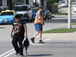 A crossing guard watches for traffic as an elementary school student crosses the road at Wyandotte Street East and Marentette Avenue in this September 2015 file photo.