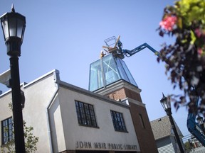 Workers install the glass dome on top of the tower at the new John Muir Public Library in Olde Sandwich Town, Wednesday, September 18, 2019.