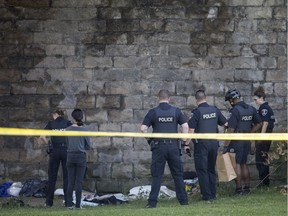 Windsor police officers investigate under the Riverside Drive West bridge, east of Crawford Avenue, along the riverfront on Friday, Sept. 20, 2019.