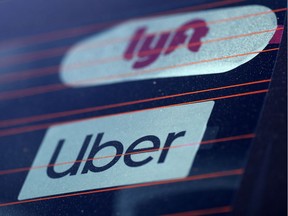 FILE PHOTO: Uber and Lyft signs are seen on a car in Redondo Beach, California, U.S., March 25, 2019.