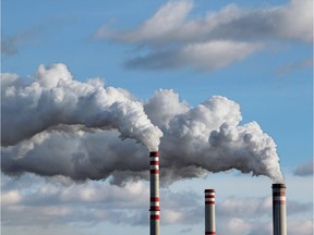 White smoke coming from smokestacks in a polluted sky. Carbon pollution. Getty Images.