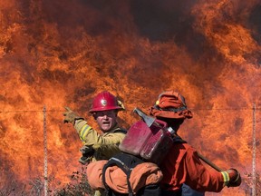 Firefighters prepare to put out flames on the road leading to the Reagan Library during the Easy Fire in Simi Valley, California on Oct. 30, 2019. - Firefighters in California battled a new fast-moving blaze on Wednesday that threatened the Ronald Reagan Presidential Library, as rare "extreme" red flag warnings were issued for much of the Los Angeles region.