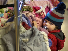 Mason Bakos plays in the rack of coats on display during the annual Coats for Kids campaign at the Unemployed Help Centre in this file photo from Nov. 12, 2016.