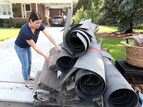 In this Aug. 30, 2017, photo, Jennifer Zazula stacks rolls of carpet from her basement after her Windsor home was flooded during heavy rainfall.