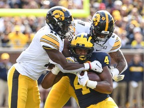 Michigan Wolverines wide receiver Nico Collins is tackled by Iowa Hawkeyes defensive back Michael Ojemudia and defensive back Geno Stone during the fourth quarter at Michigan Stadium.