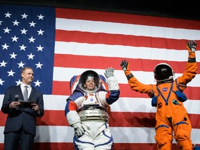 Amy Ross, NASA spacesuit engineer, left, and NASA Administrator Jim Bridenstine, second from left, watch as Kristine Davis, NASA spacesuit engineer, wearing a ground prototype of NASA’s new Exploration Extravehicular Mobility Unit (xEMU), and Dustin Gohmert, Orion Crew Survival Systems Project Manager, wearing the Orion Crew Survival System suit, right, wave Tuesday, Oct. 15, 2019 at NASA Headquarters in Washington.