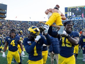 Ambry Thomas and teammate Christopher Hinton of the Michigan Wolverines celebrate a win over the Michigan State Spartans at Michigan Stadium on November 16, 2019 in Ann Arbor, Michigan. Michigan defeated Michigan State Spartans 44-10.