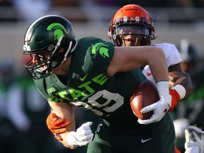 Matt Dotson of the Michigan State Spartans battles for extra yards after a first half catch against Milo Eifler of the Illinois Fighting Illini at Spartan Stadium on November 09, 2019 in East Lansing, Michigan.