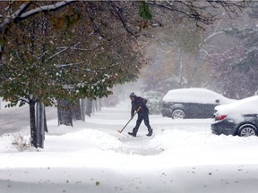 With a cover of green leaves mixed with a heavy snowfall, Zoley Banka shovels the sidewalk on 2200 block of Lincoln Road Monday Nov. 11, 2019.