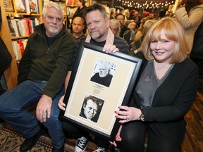 The children of Eugene McNamara, David McNamara, left, Chris McNamara and Mary McNamara, right, pose with a framed memorial of their late father during a celebration of over 50 years of The Windsor Review at Biblioasis Bookshop Thursday evening.  Eugene McNamara first published The Windsor Review in 1965.