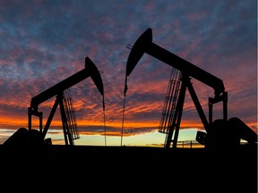 Dramatic sky over two pumpjacks in rural Alberta, Canada. These jacks can extract between 5 to 40 litres of crude oil and water emulsion at each stroke.