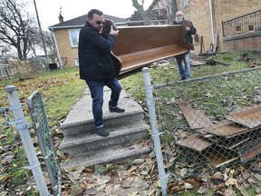Jody Learn, left, and Rob Livingstone carry a discarded pew at the Holy Apostolic Catholic Assyrian Church of East St. Thomas Parish in Windsor on Monday, November 25, 2019. The pews which were on the front lawn of the Giles Blvd. church were free for the taking on a first come first served basis.