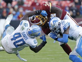 Washington Redskins running back Wendell Smallwood is tackled while carrying the ball by Detroit Lions middle linebacker Jarrad Davis and Lions strong safety Tavon Wilson in the fourth quarter at FedExField.
