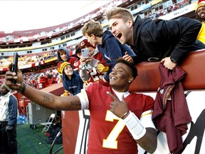 Washington Redskins quarterback Dwayne Haskins takes selfies with fans during the second half of an NFL football game against the Detroit Lions, Sunday, Nov. 24, 2019, in Landover, Md. The Redskins won 19-16.