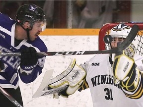Western's Kolten Olynek swats at the puck in front of Windsor Lancers' goalie Jon Reinhart during Friday's OUA men's hockey game at the Capri Complex.