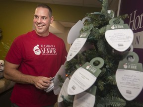 Ryan Jershy, co-owner of Home Instead Senior Care, places Be A Santa placards on their Christmas Tree in the lobby, Monday, Nov. 4, 2019.