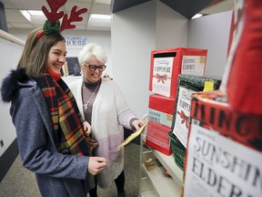Emily Truman, left, and Kitty Pope, CEO of Windsor Public Library, look over hundreds of handmade Christmas cards at the downtown central branch on Tuesday. The 16-year-old is aiming to collect and distribute 10,000 cards for seniors in Windsor-Essex nursing homes.