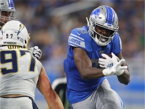 Kerryon Johnson of the Detroit Lions looks for yards during a second quarter run behind Joey Bosa #97 of the Los Angeles Chargers at Ford Field on September 15, 2019 in Detroit, Michigan.