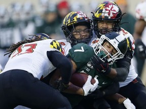 Wide receiver Cody White of the Michigan State Spartans is tackled by linebacker Fa'Najae Gotay, defensive back Marcus Lewis and linebacker Isaiah Davis of the Maryland Terrapins during the first half at Spartan Stadium on November 30, 2019, in East Lansing, Michigan.