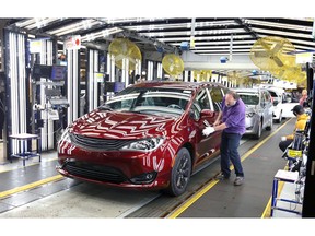Inspector Frank Calzavara, front, with a Chrysler Pacifica Hybrid in velvet red in the Final Car area of FCA Windsor Assembly Plant.