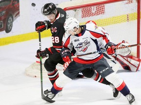 Niagara Icedogs Andrew Bruder, left, tips the puck wide of the net while being checked by Windsor Spitfires Louka Henaut in OHL action from WFCU Centre on Saturday.