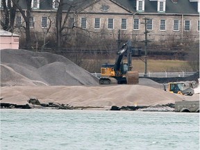 Heavy machinery move tons of crushed stone around the Detroit, Michigan shoreline at Detroit Bulk Storage Wednesday.  Historic Fort Wayne is shown behind.