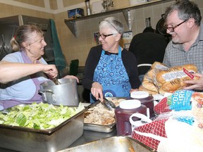 Rodger Fordham, right, director of Feeding Windsor, stops by the kitchen of New Song Church where volunteers were busy preparing a multiple course Christmas dinner Saturday. Assisting with food preparations were Jane Michaud, left and Ruth Sylvestre.  New Song Church host about 300 area residents for a free Christmas dinner complete with entertainment from a live band.