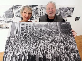 Elaine Weeks and Chris Edwards of Walkerville Publishing pose with a vintage 1910 photograph of Ford workers at Artspeak Gallery Tuesday. The two have recently published Windsor: Before & After, which shows the city's many existing and demolished heritage buildings.