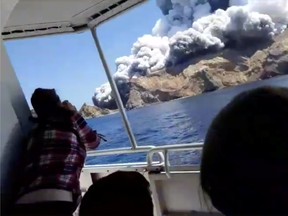 People on a boat react as smoke billows from the volcanic eruption of Whakaari, also known as White Island, New Zealand December 9, 2019 in this picture grab obtained from a social media video. INSTAGRAM @ALLESSANDROKAUFFMANN/via REUTERS T
