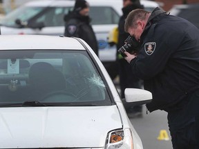 A Windsor police officer takes photos of a white Nissan involved in a collision with a pedestrian on Tecumseh Road East on Dec. 12, 2019.