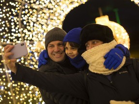 Martin, Maria, and Isi De La Orden, 6, pose for a family selfie under the lights at the opening of the third annual Bright Lights Windsor at Jackson Park, Dec. 6, 2019.
